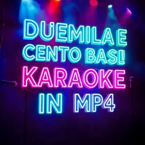 Puede incluir: Letrero de neón con las palabras "DUEMILA E CENTO BASI! KARAOKE IN MP4" en azul y rosa. El letrero está en una habitación oscura con iluminación de escenario y una bola de discoteca. Un soporte de micrófono es visible en primer plano.