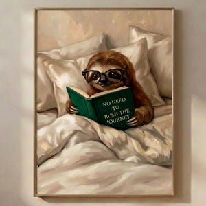 The framed sloth reading print in a thin gold frame on a warm plaster wall above a wooden floor