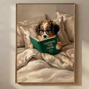 Könnte beinhalten: Ein gerahmter Wandkunstdruck, der einen braun-weißen Welpen mit schwarz umrandeter Brille zeigt, der in einem Bett unter weichen beigen Decken liegt. Der Welpe hält ein offenes grünes Buch mit dem goldenen Text PAWSING THE PANIC und einem Herz.