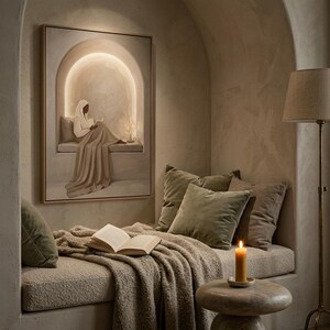 May include: A framed rectangular wall art piece depicting a figure in a white head covering and robe reading a book within an arched alcove. The artwork features soft beige and cream tones with a glowing light effect surrounding the central figure.