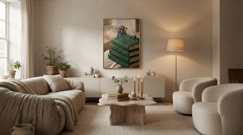 Wide view of a neutral living room with the pigeon peeking over books print framed above a low sofa in soft daylight