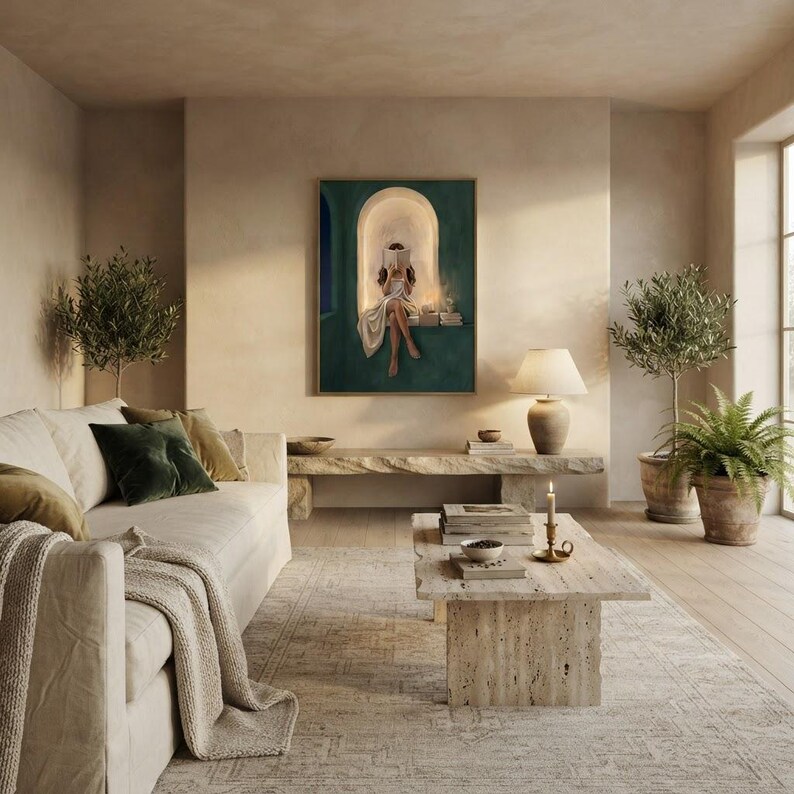 Emerald green reading nook art print in a thin gold frame on a warm plaster wall in a sunlit living room, above a travertine bench with a linen sofa, olive trees and a potted fern.