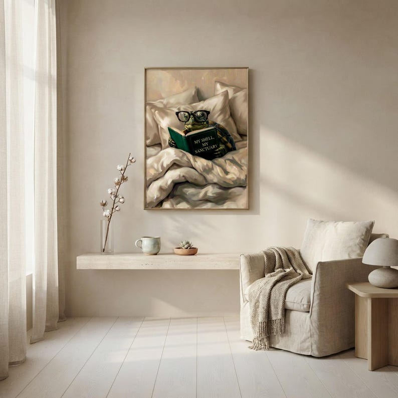 The tortoise reading print framed above a floating shelf beside an armchair with a draped throw and a sheer curtain in soft daylight