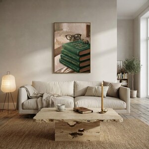 Turtle peeking over books wall art framed on a warm plaster wall in a calm light-filled living room with a cream linen sofa