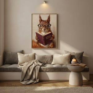 Painterly print of a red squirrel in round tortoiseshell glasses reading a wine-red book framed above a cushioned window seat with a lit candle and a folded knit throw