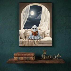 The moonlit bed ghost reading print framed on a deep teal wall above a narrow shelf with antique books and a brass candlestick
