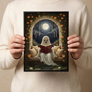 The pumpkin arch ghost reading print held in both hands by a person in a cream sweater, showing its scale