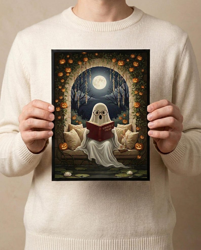 The pumpkin arch ghost reading print held in both hands by a person in a cream sweater, showing its scale
