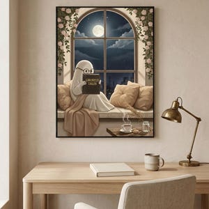 The window seat coffee ghost reading print framed above a pale oak desk with a stoneware mug and a brass lamp