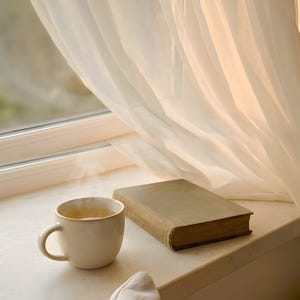 Cozy window seat wall art print with steaming coffee and book on beige ledge, sheer curtains with golden soft light, Japandi slow living interior, minimalist reading nook decor, neutral home accent, digital printable photography, calm morning ritual