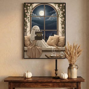 The window seat coffee ghost reading print framed above an entryway console styled for autumn with white pumpkins and dried wheat