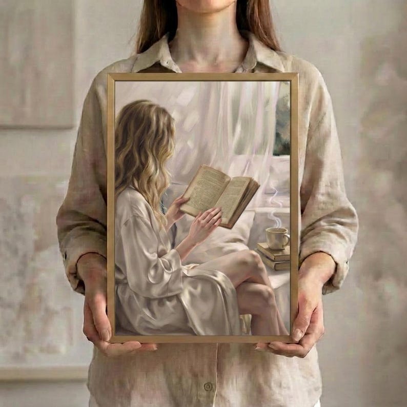 Person in a linen shirt holding the framed woman reading art print, showing its scale in the hands
