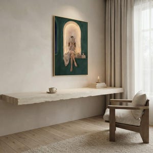 Emerald green reading nook art print on a pale plaster wall above a floating travertine ledge with a coffee cup, a candle and stacked books, beside a wooden armchair and linen curtains.