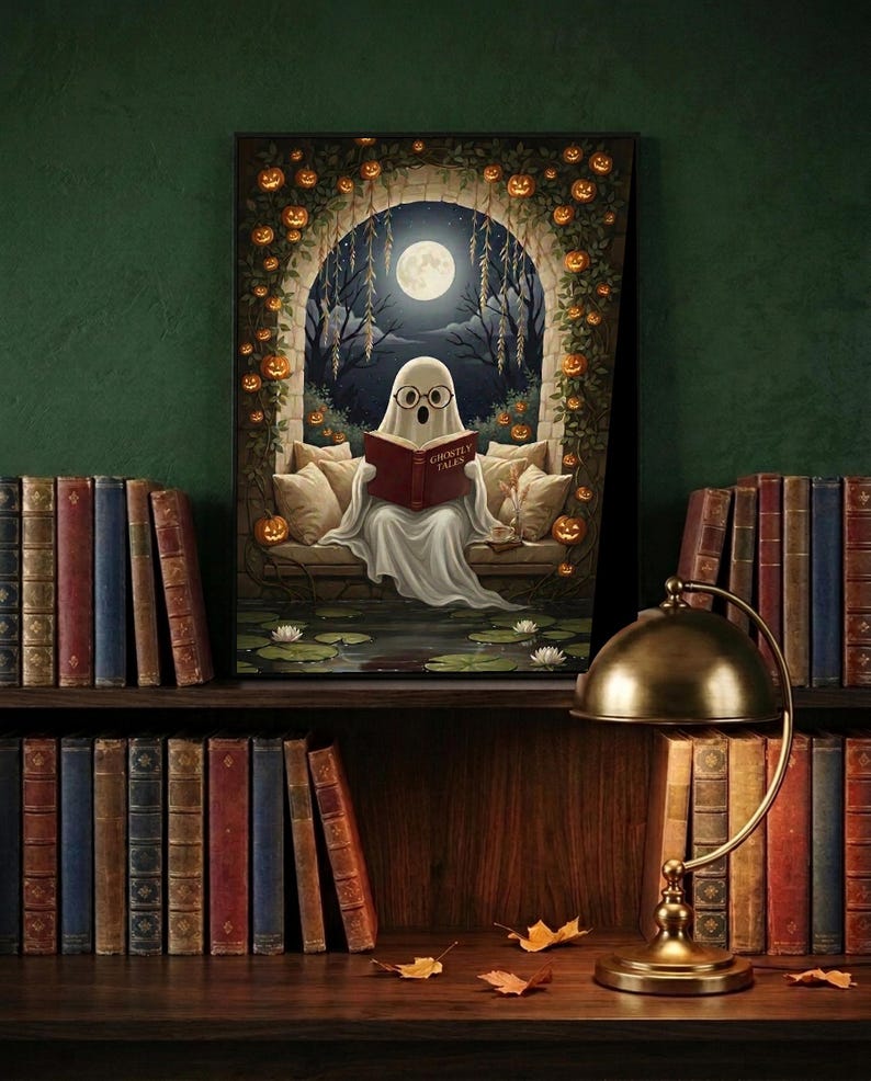 The pumpkin arch ghost reading print framed and leaning on a dark wood library shelf against a deep green wall