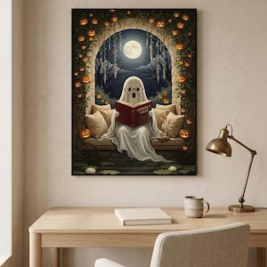 The pumpkin arch ghost reading print framed above a pale oak desk with a stoneware mug and a brass lamp