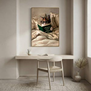 The cat reading print framed above a pale desk in a quiet, minimal workspace