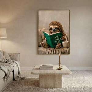 Wide view of a neutral living room with the sloth reading print framed above a low sofa in soft daylight
