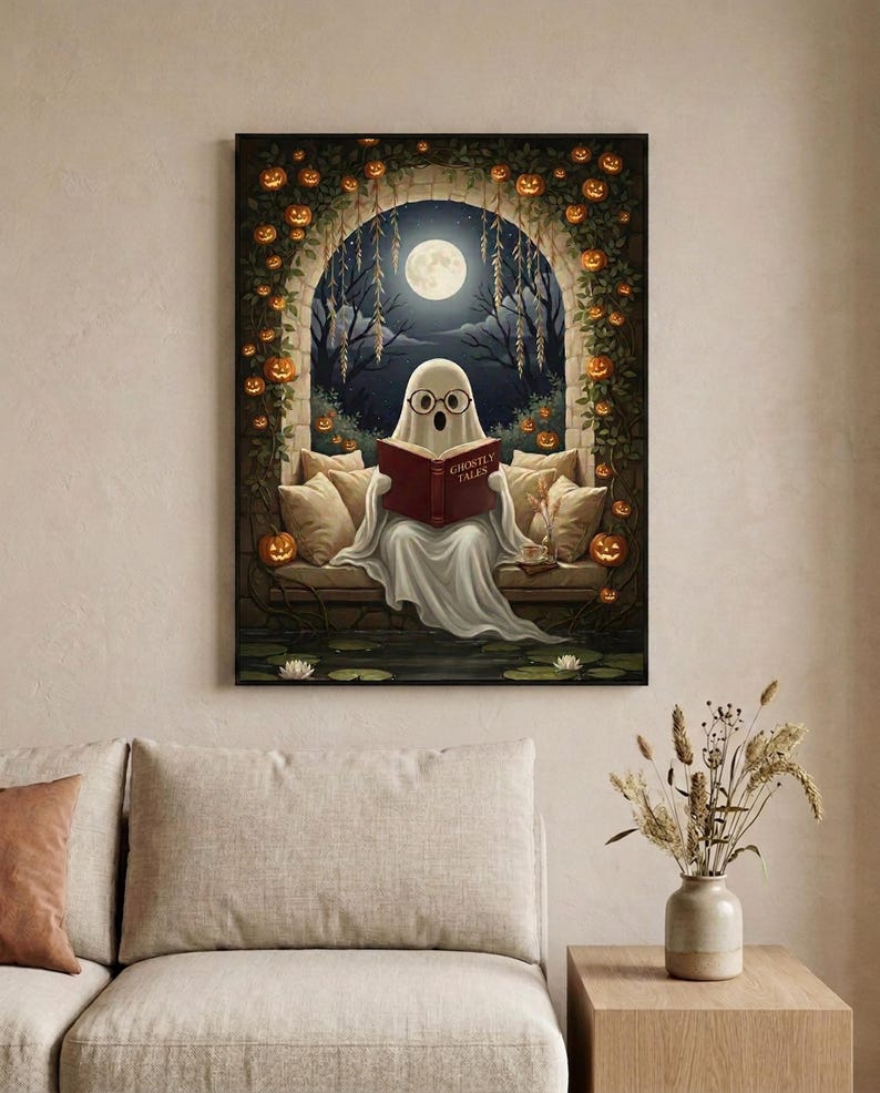 The pumpkin arch ghost reading print framed in a calm neutral living room above a linen sofa
