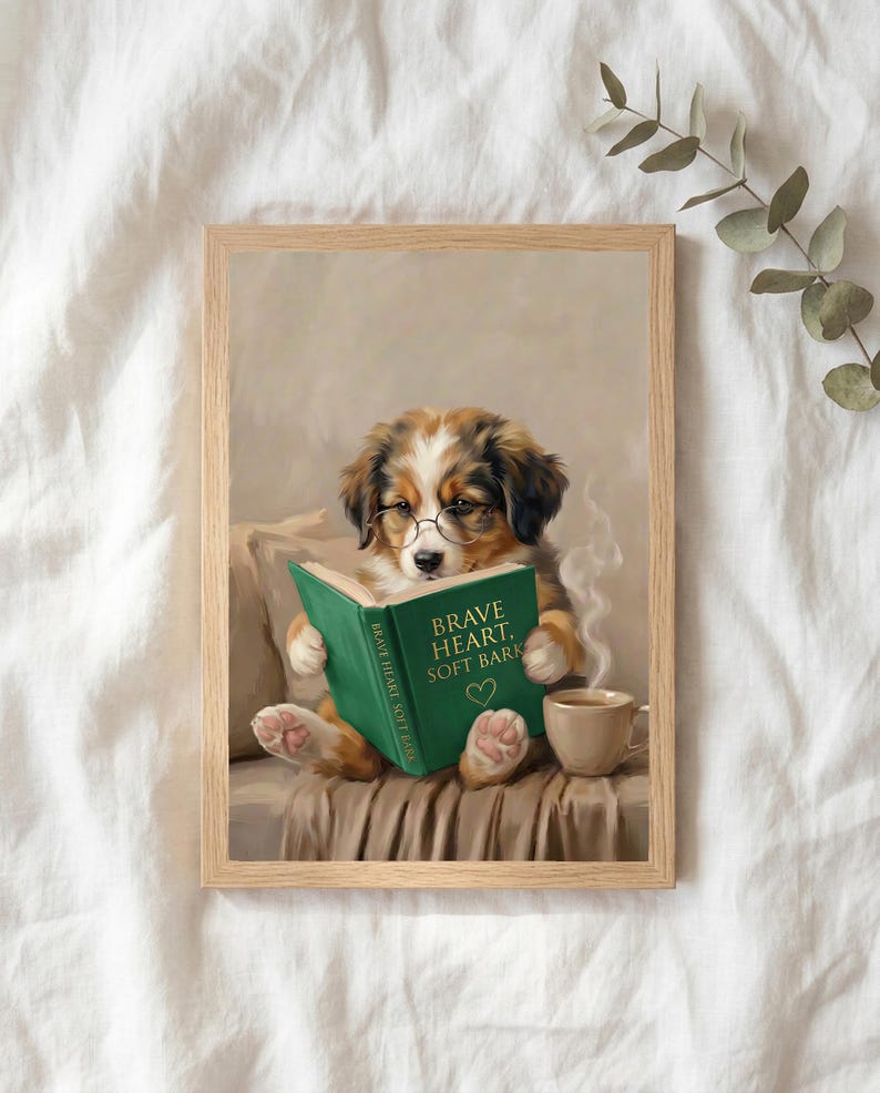 The puppy reading print in a thin natural oak frame lying on white linen with a sprig of eucalyptus