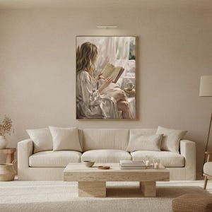 Wide view of a neutral living room with the woman reading print framed in gold on a warm plaster wall between linen curtains