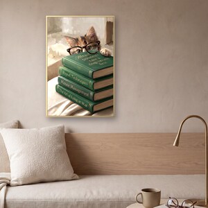 The framed cat peeking over books print above a low bench with a pale oak back panel, a bouclé cushion and a linen seat, beside a brass arc lamp and a small table holding a mug and a pair of reading glasses.