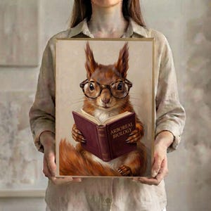 A person in a linen shirt holding the framed print in a slim gold frame