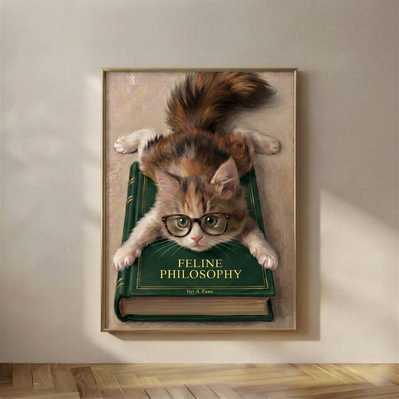 cat with glasses splooting wall art on top of a bookish "feline philosophy" book.