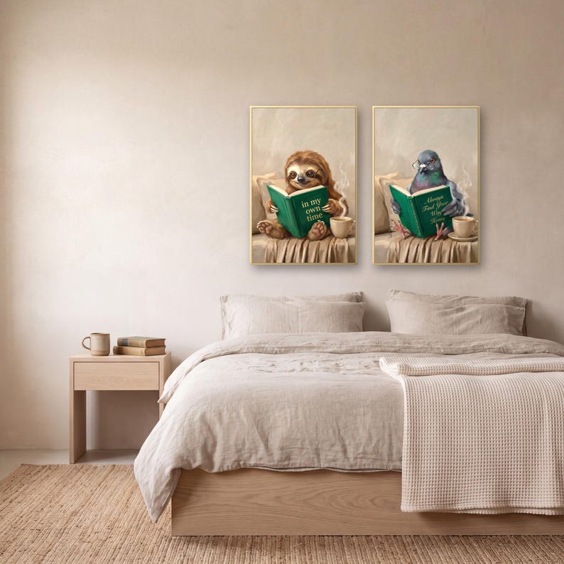 Two prints from the set, the sloth and the pigeon, in gold frames above a bed made up in linen bedding, with a pale oak nightstand alongside