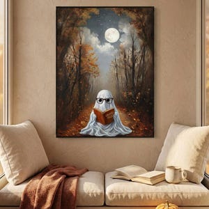 The autumn forest ghost reading print framed above a cushioned window bench with a wool throw and a small pumpkin