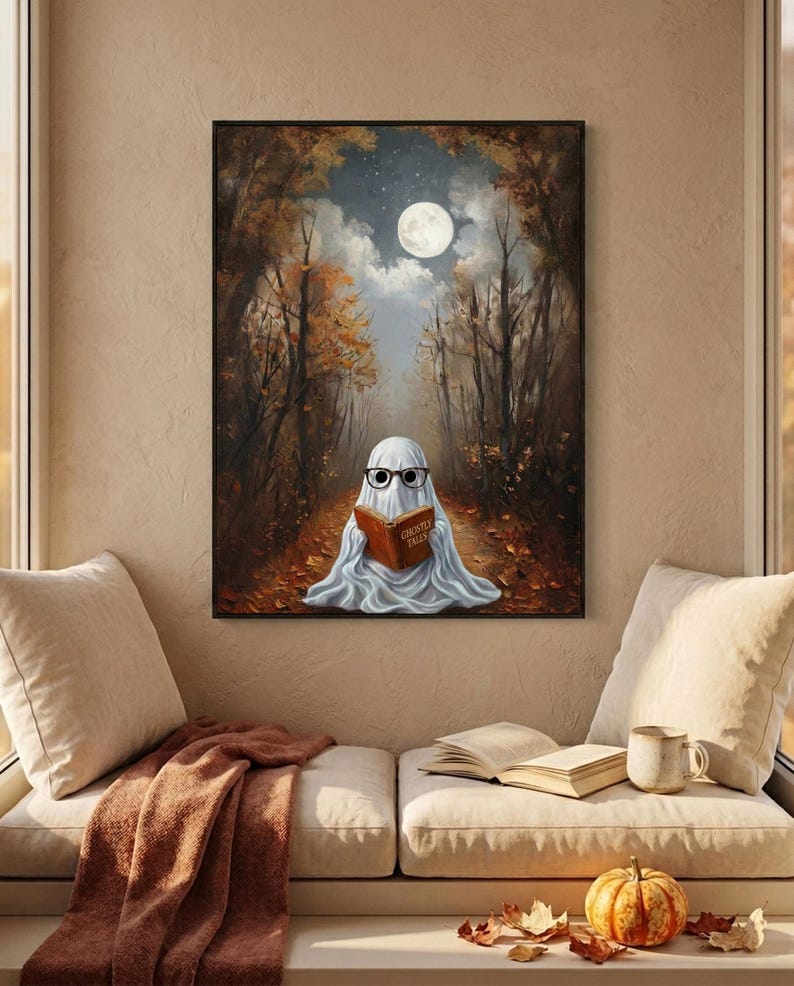 The autumn forest ghost reading print framed above a cushioned window bench with a wool throw and a small pumpkin
