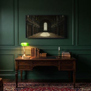 Arched reading room art from the set on a Frame TV in a dark academia study with a green panelled wall, walnut desk, green banker's lamp, leather armchair and Persian rug