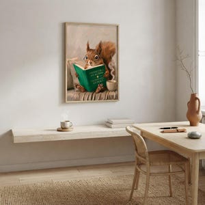 Squirrel in glasses reading print framed above a restrained workspace with pale walls and a natural linen chair