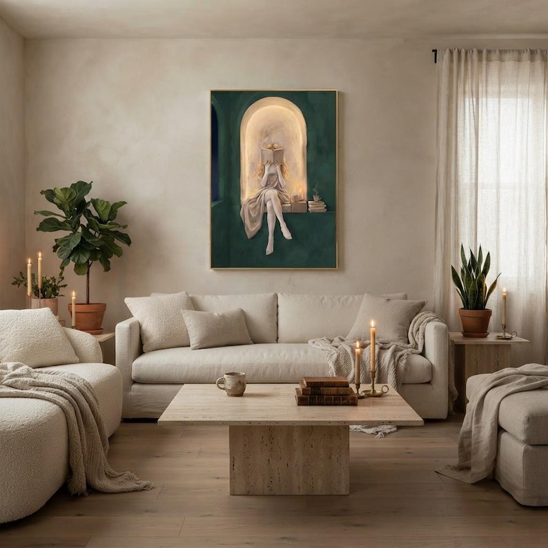 Emerald green reading nook art print in a thin gold frame on a plaster wall above a cream linen sofa, with boucle armchairs, a travertine coffee table, lit tapers and a fiddle-leaf fig.