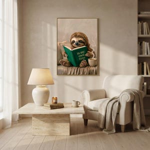 Sloth reading wall art framed on a warm plaster wall in a calm light-filled living room with a cream linen sofa