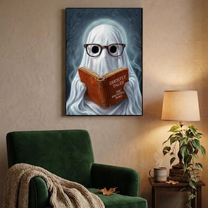 The ghost reading print above a green velvet armchair with a knit throw, a warm lamp and a stack of old books
