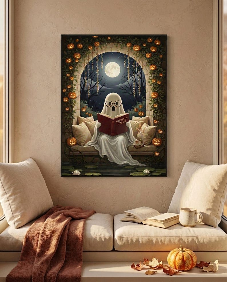The pumpkin arch ghost reading print framed above a cushioned window bench with a wool throw and a small pumpkin