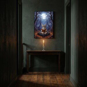 The kitten and ghosts ghost reading print framed alone in a dim charcoal-green hallway above a console with a single lit candle