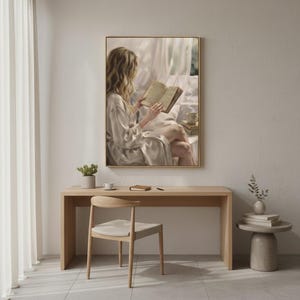 Minimal oak desk and chair against a pale wall with the woman reading print hanging in a slim gold frame above