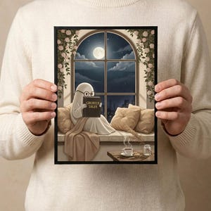 The window seat coffee ghost reading print held in both hands by a person in a cream sweater, showing its scale