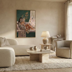 Emerald green wall art print framed in gold above a boucle sectional sofa and a linen armchair in a bright, minimalist living room with a travertine coffee table.