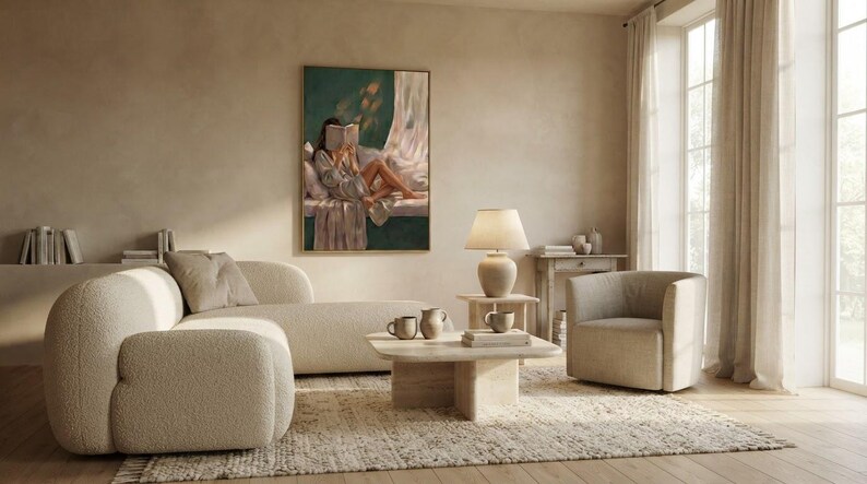 Emerald green wall art print framed in gold above a boucle sectional sofa and a linen armchair in a bright, minimalist living room with a travertine coffee table.