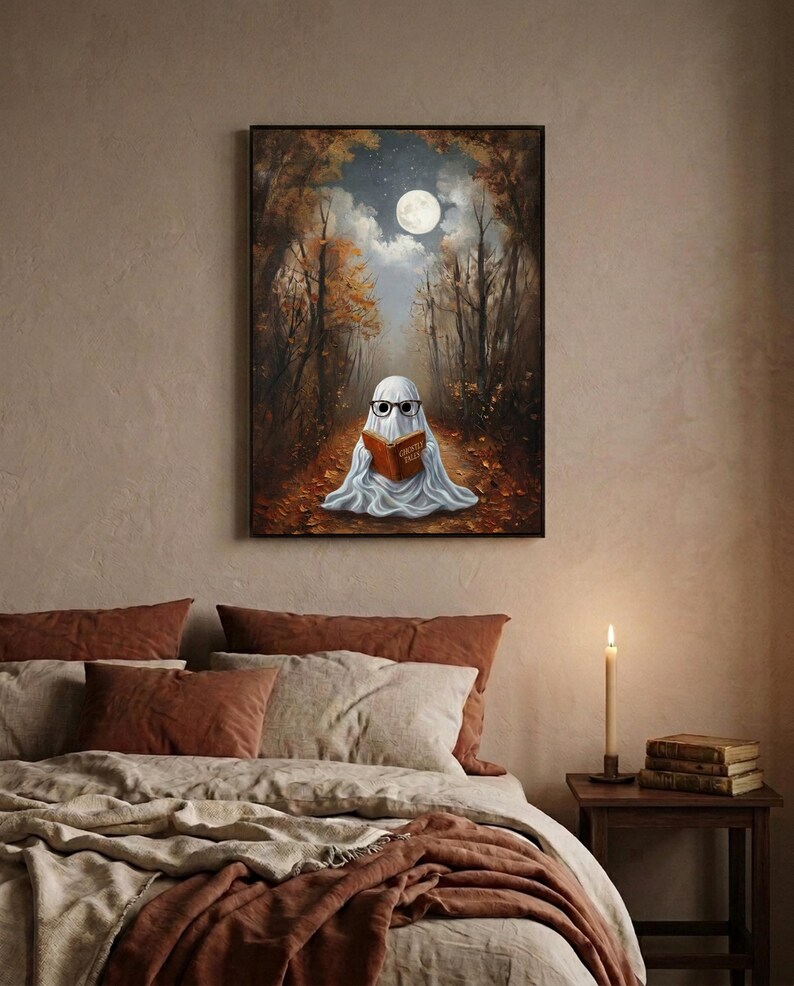 The autumn forest ghost reading print framed above a bed with linen bedding and a lit candle on the nightstand