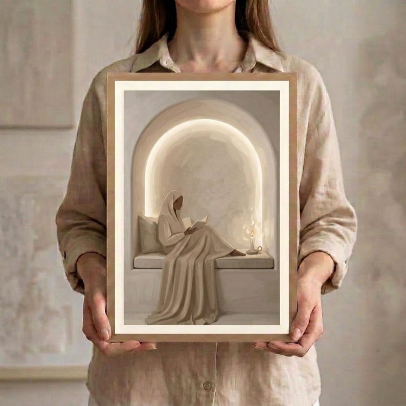 May include: A rectangular framed wall art print featuring a beige-toned illustration of a figure draped in fabric sitting within an arched alcove. The figure holds an open book, illuminated by a glowing light source and a small candle on a ledge.