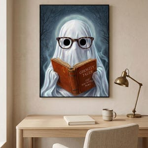 The ghost reading print above a pale oak desk with a stoneware mug, a brass lamp and a notebook