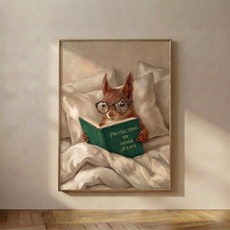 The framed squirrel reading print in a thin gold frame on a warm plaster wall above a wooden floor