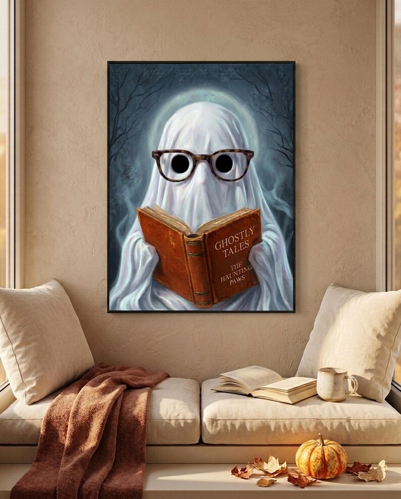 The ghost reading print hanging above a cushioned window bench with a wool throw and a small pumpkin on the sill