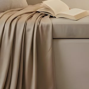 Close-up detail from Reading Nook Quiet Corner, a cropped fragment of the printable artwork: a linen throw draped over a window seat with an open book and a ceramic mug.