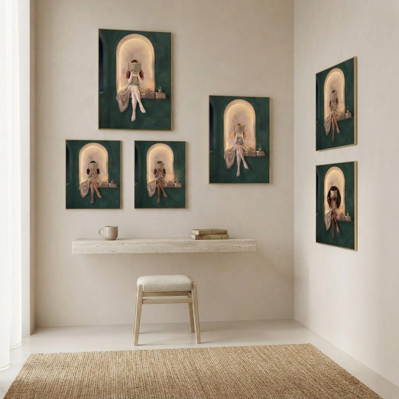 Six emerald green reading nook art prints wrapped around a corner in thin gold frames, above a floating travertine desk with a mug, books and a linen-topped stool.