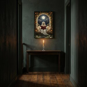 The pumpkin arch ghost reading print framed alone in a dim charcoal-green hallway above a console with a single lit candle
