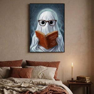 The ghost reading print framed above a bed with linen bedding and a lit candle on the nightstand